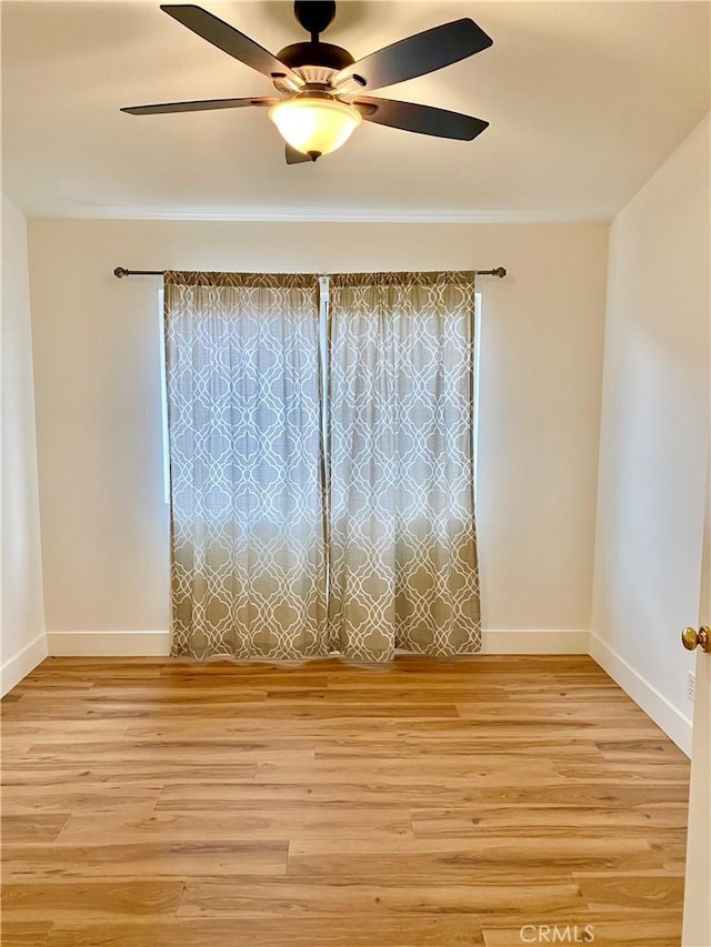 empty room featuring baseboards, light wood finished floors, and ceiling fan