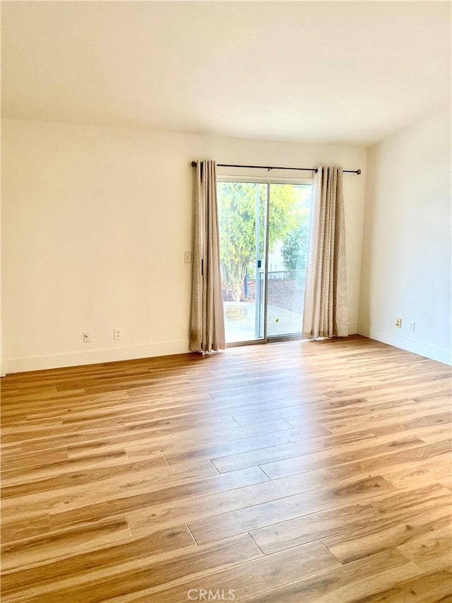 spare room featuring baseboards and light wood finished floors