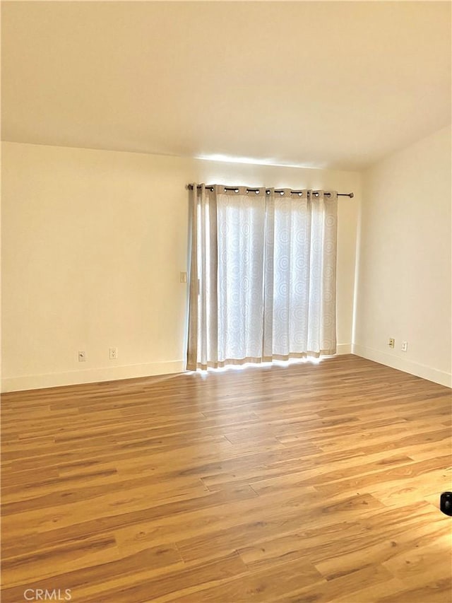 unfurnished room with baseboards and light wood-style floors