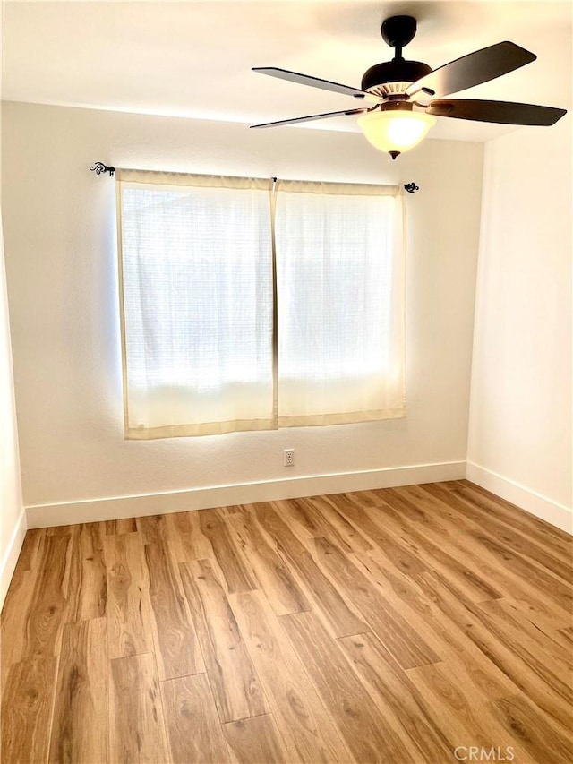 unfurnished room featuring a wealth of natural light, light wood-type flooring, baseboards, and ceiling fan