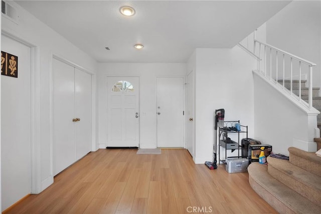 foyer with visible vents, stairs, and light wood-style floors