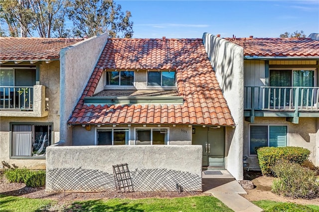 exterior space with stucco siding, a tiled roof, and a balcony