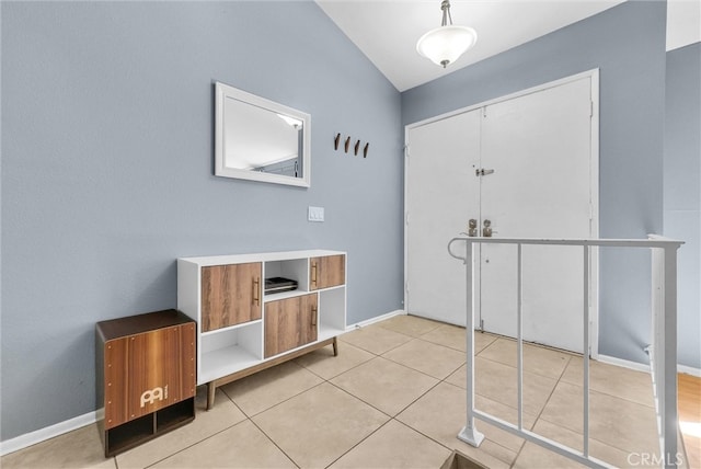 entrance foyer with light tile patterned flooring, baseboards, and vaulted ceiling