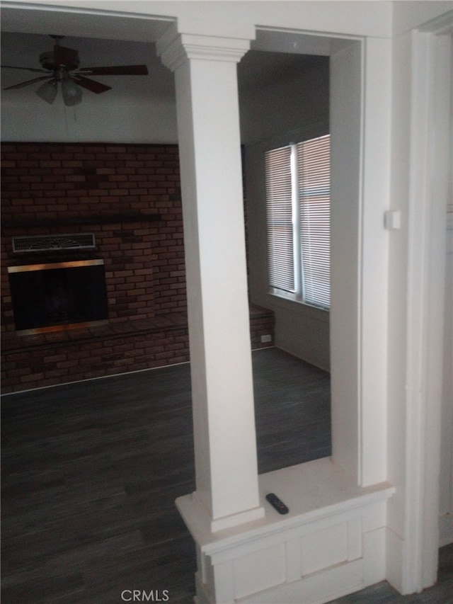 unfurnished living room with wood finished floors, brick wall, and ceiling fan