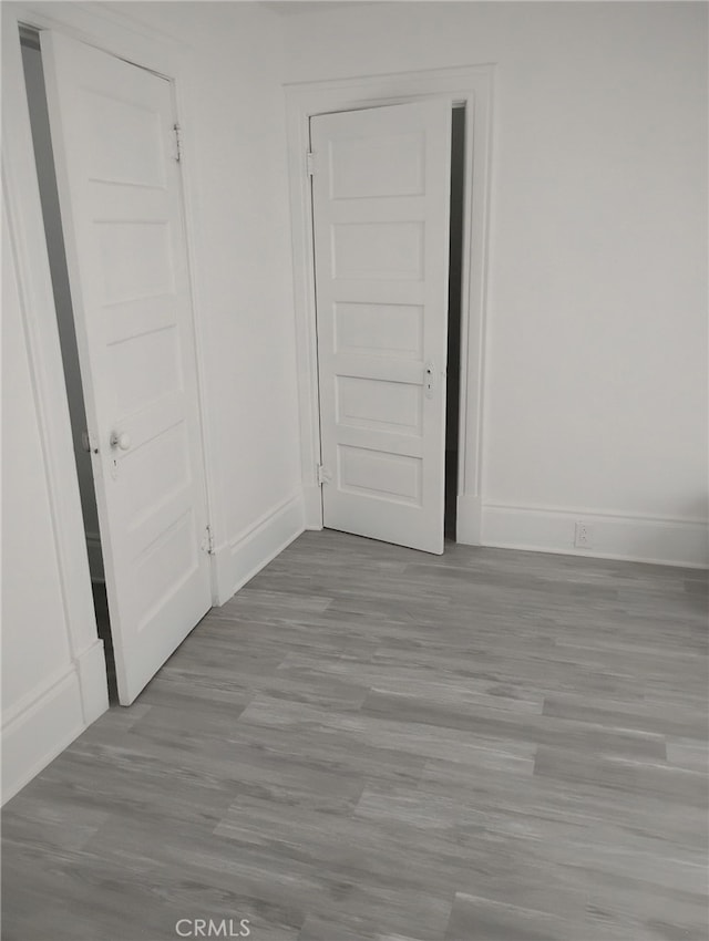 spare room with baseboards and wood finished floors