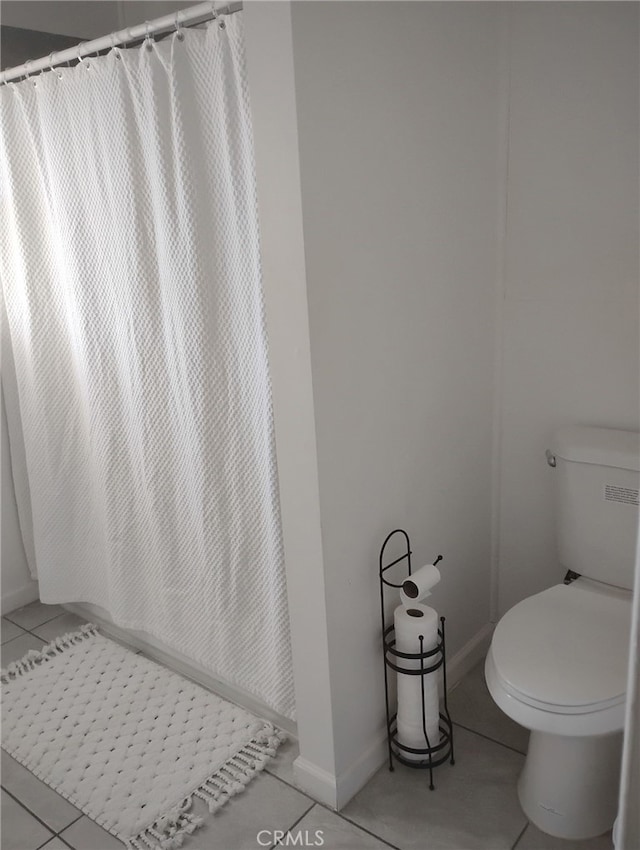 full bathroom with curtained shower, tile patterned floors, toilet, and baseboards