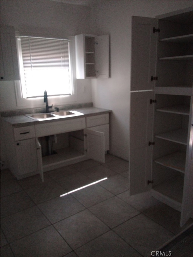 kitchen featuring white cabinetry, open shelves, light tile patterned floors, and a sink