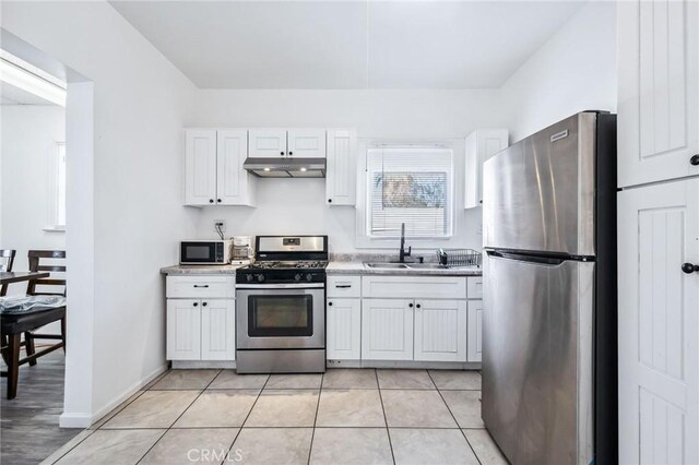401 Cibola St, Needles, CA 92363 - kitchen with appliances with stainless steel finishes, under cabinet range hood, a sink, white cabinetry, and light tile patterned floors