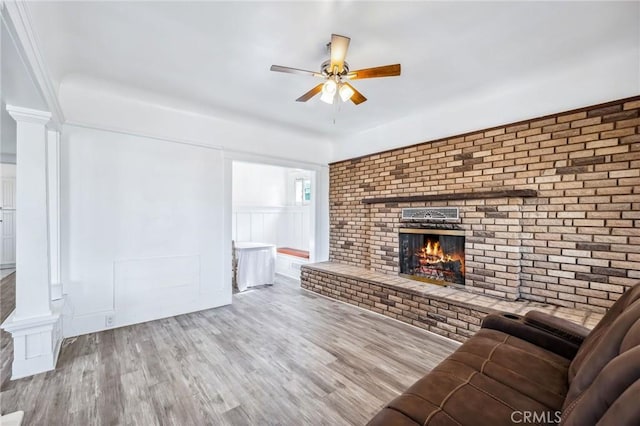 401 Cibola St, Needles, CA 92363 - living area featuring ceiling fan, decorative columns, a brick fireplace, wood finished floors, and a decorative wall