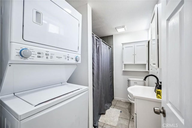 401 Cibola St, Needles, CA 92363 - laundry room featuring stacked washer and clothes dryer, light tile patterned floors, baseboards, and a textured ceiling