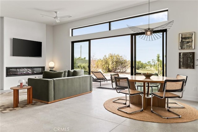 interior space featuring a glass covered fireplace, a ceiling fan, and concrete flooring