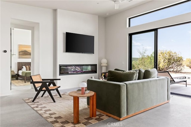 living area with a glass covered fireplace and finished concrete flooring