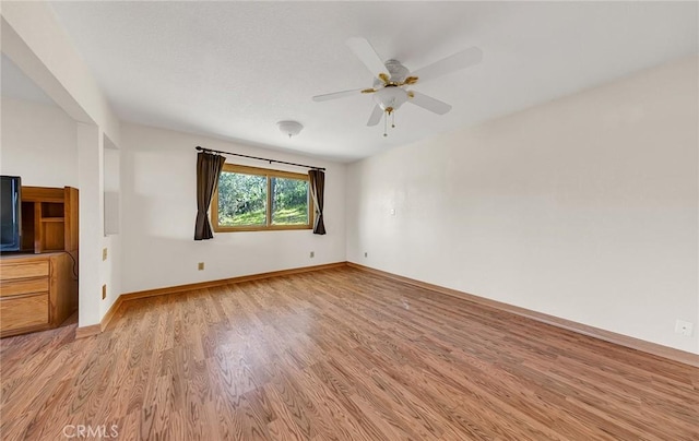 spare room featuring a ceiling fan, light wood-style floors, and baseboards