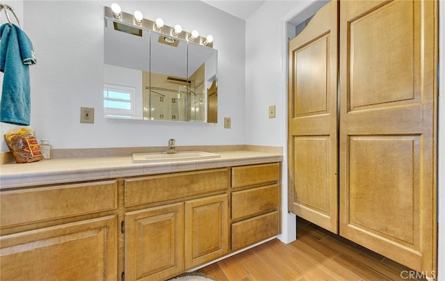 bathroom with a stall shower, vanity, and wood finished floors