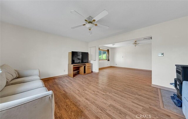 living room with baseboards, a ceiling fan, and light wood-style floors