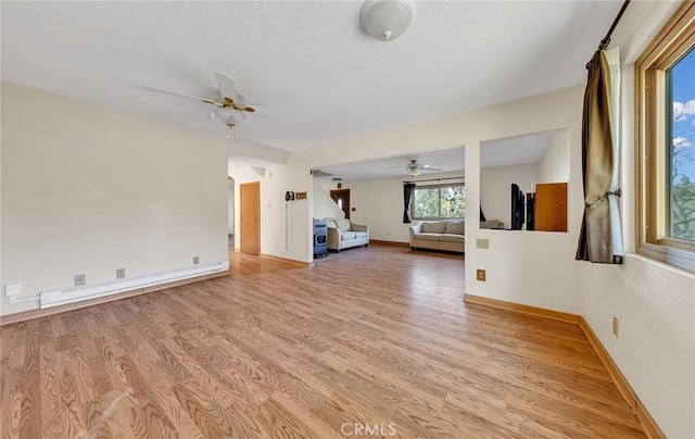 unfurnished living room with a baseboard heating unit, baseboards, ceiling fan, and light wood finished floors