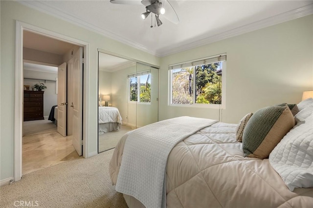 bedroom with a closet, crown molding, baseboards, light colored carpet, and ceiling fan