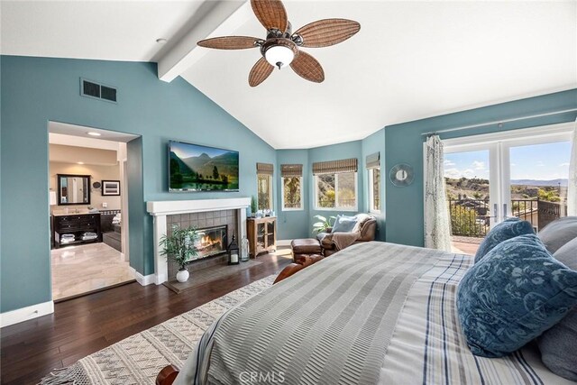 bedroom with wood finished floors, visible vents, baseboards, lofted ceiling with beams, and a tiled fireplace