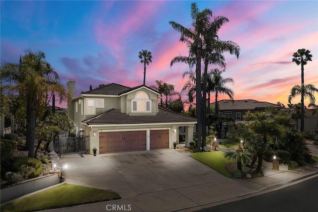 view of front of home featuring stucco siding, a gate, a tile roof, concrete driveway, and an attached garage