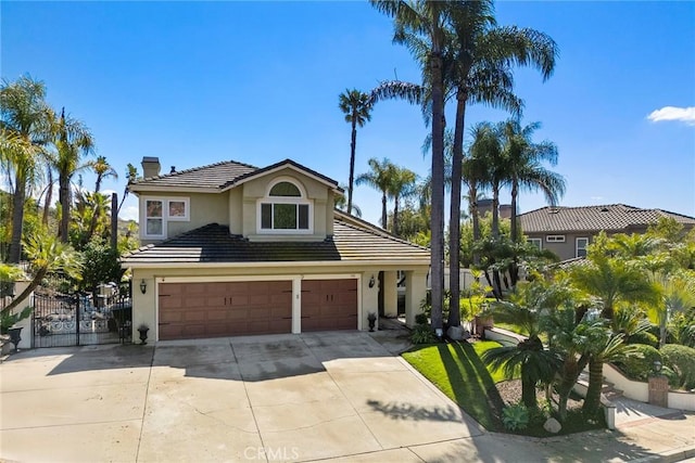 traditional-style home with a tiled roof, stucco siding, a chimney, driveway, and a gate