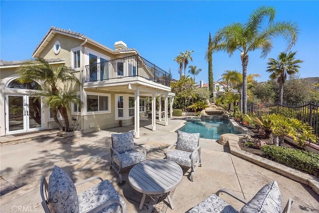 back of property with a balcony, fence, stucco siding, french doors, and a patio area