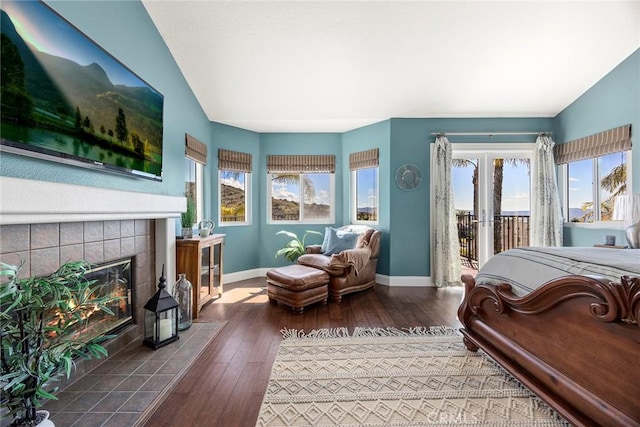 bedroom with multiple windows, hardwood / wood-style floors, a fireplace, and access to outside