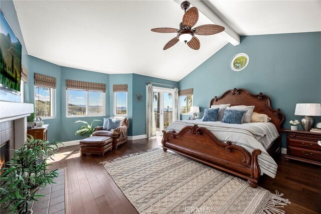 bedroom featuring a tiled fireplace, multiple windows, baseboards, and hardwood / wood-style floors