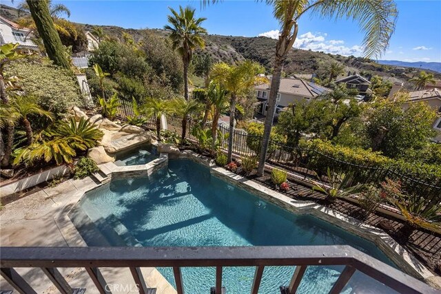 view of pool featuring a mountain view, a pool with connected hot tub, and fence