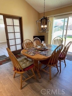 dining area with a chandelier, lofted ceiling, a textured ceiling, and wood finished floors