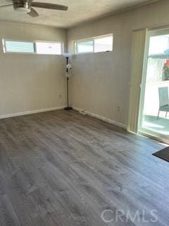 empty room featuring ceiling fan, baseboards, and wood finished floors