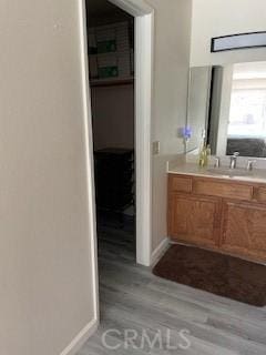 bathroom with vanity, wood finished floors, and baseboards