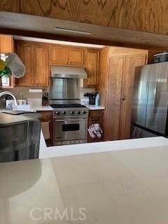 kitchen featuring ventilation hood, appliances with stainless steel finishes, brown cabinetry, and light countertops