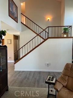 unfurnished living room featuring baseboards, wood finished floors, a towering ceiling, and stairs