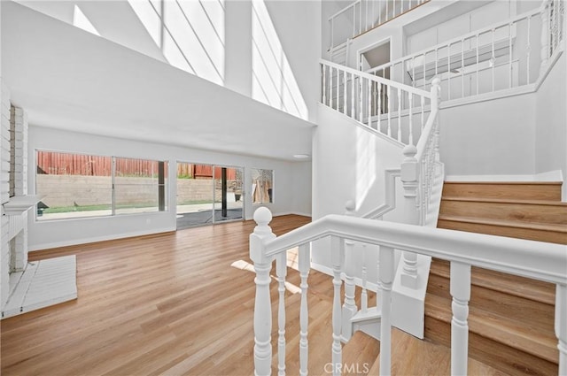 stairway featuring a high ceiling, a skylight, wood finished floors, and baseboards