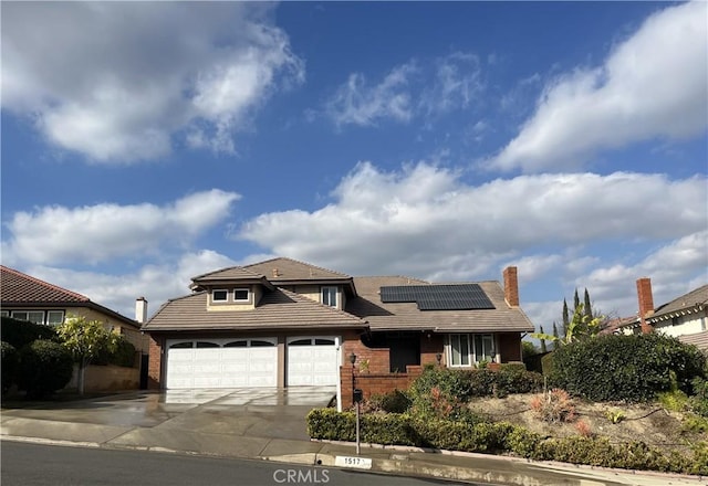 view of front of home featuring brick siding, solar panels, a tile roof, concrete driveway, and a garage