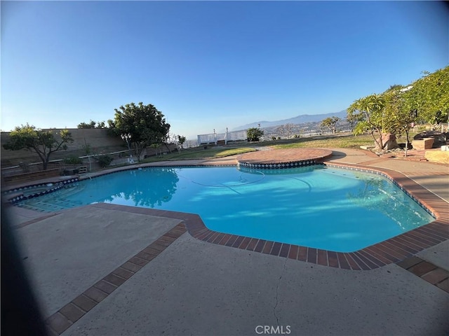 outdoor pool with a patio, fence, and a mountain view