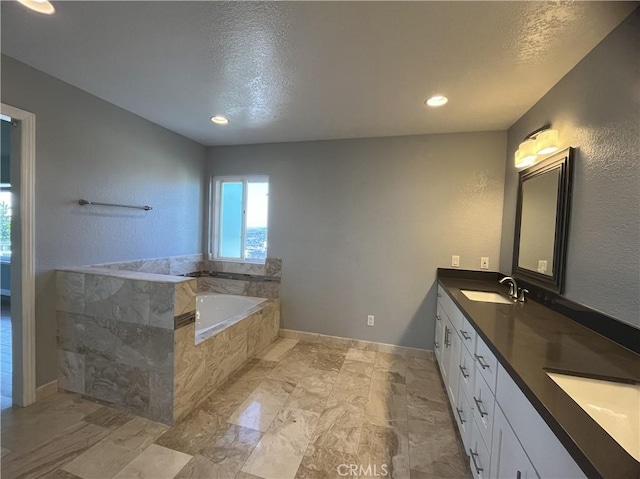 full bathroom with a sink, a textured ceiling, double vanity, baseboards, and a bath