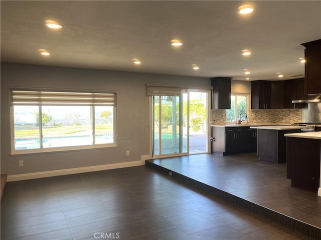 kitchen featuring backsplash, a center island, baseboards, light countertops, and a sink