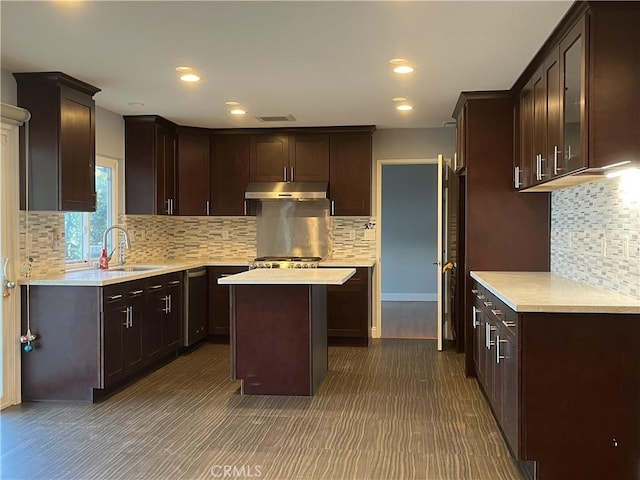 kitchen featuring visible vents, dark brown cabinets, under cabinet range hood, light countertops, and a sink