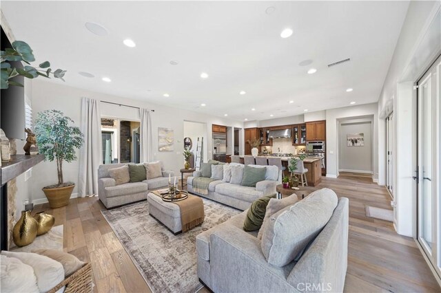 living room featuring recessed lighting, visible vents, light wood-style flooring, and plenty of natural light