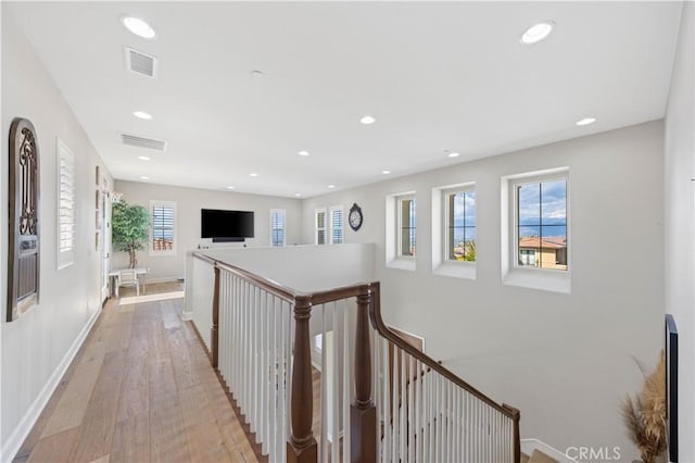 hall with light wood-style floors, recessed lighting, an upstairs landing, and visible vents