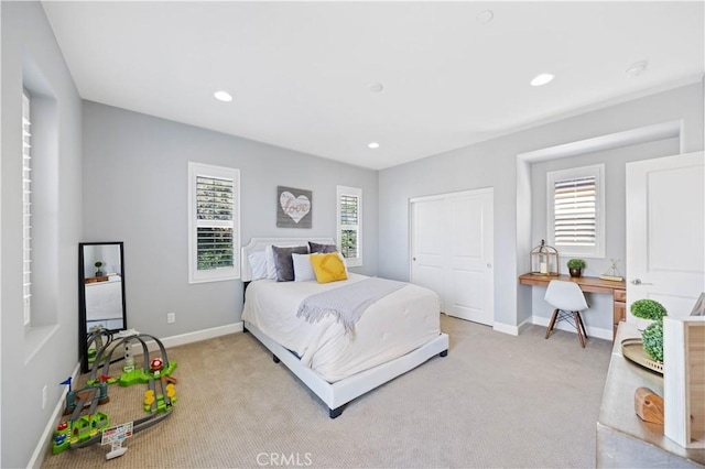 bedroom with baseboards, multiple windows, and light colored carpet