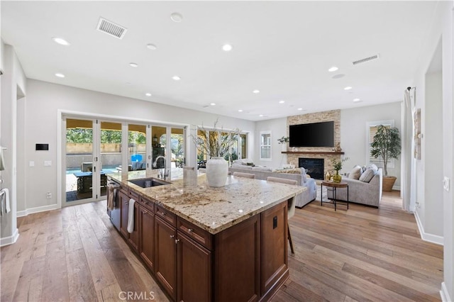 kitchen featuring light wood-style floors, a fireplace, visible vents, and a sink