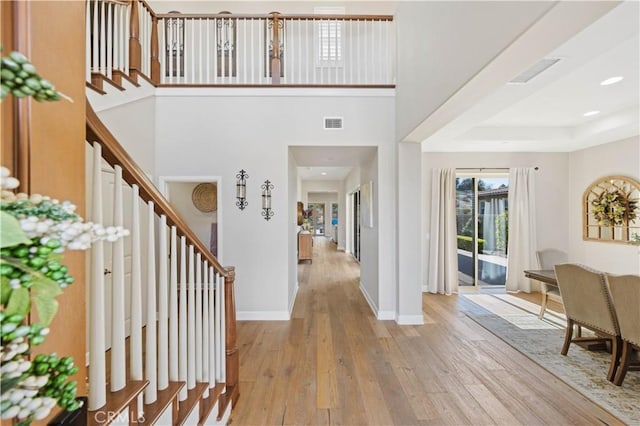 foyer with stairs, visible vents, wood finished floors, and baseboards