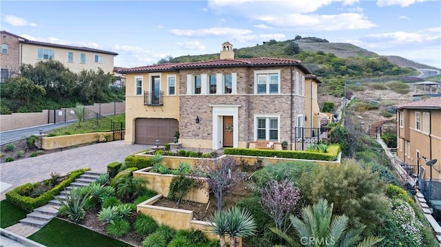 mediterranean / spanish-style home with fence, a vegetable garden, a chimney, a garage, and decorative driveway