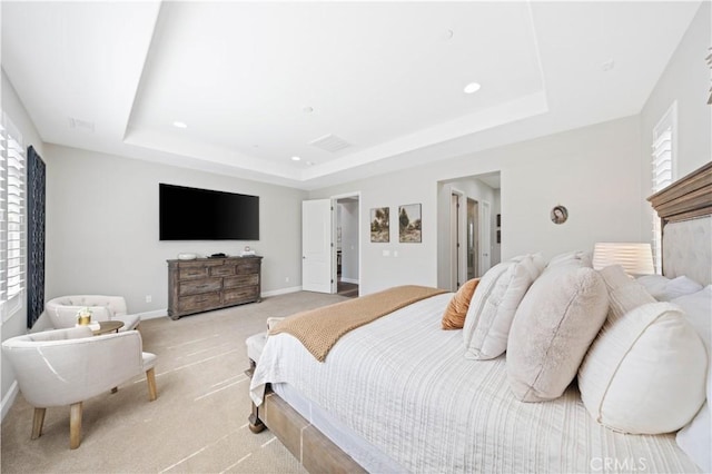 bedroom with a tray ceiling, multiple windows, and light carpet