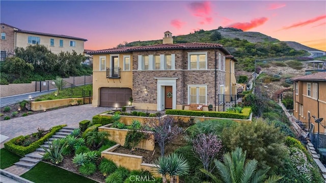 mediterranean / spanish-style home featuring fence, a garden, a chimney, a garage, and decorative driveway