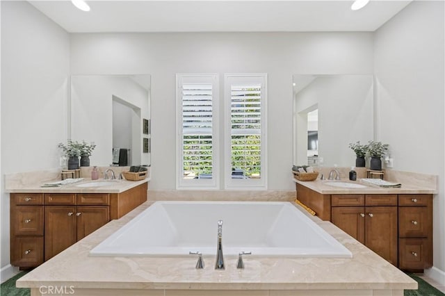 bathroom featuring a bath, two vanities, and a sink