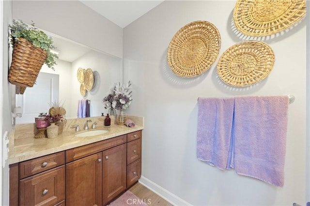 bathroom featuring vanity, wood finished floors, and baseboards