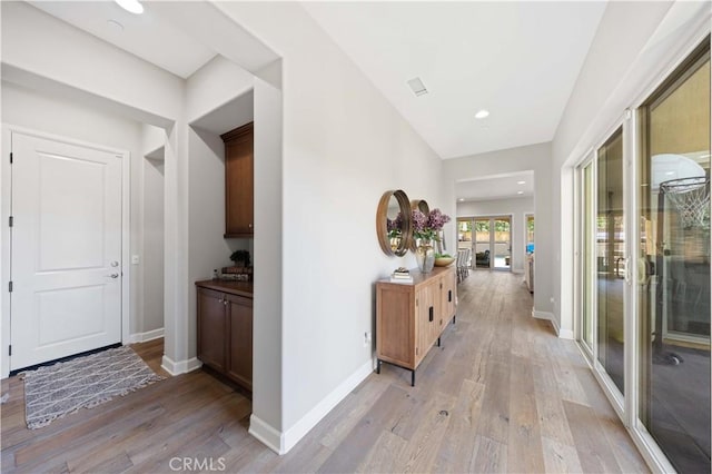 hall featuring light wood-style flooring, french doors, and baseboards